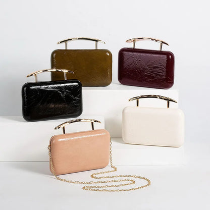 Textured rectangular evening bag with curved metal handle — five colors arranged on white display blocks | BTendance