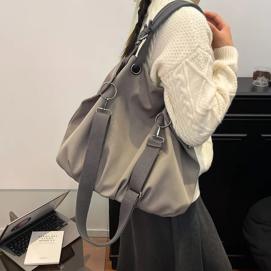 Slouchy nylon shoulder bag with contrasting grey handles — grey worn over cream sweater | BTendance