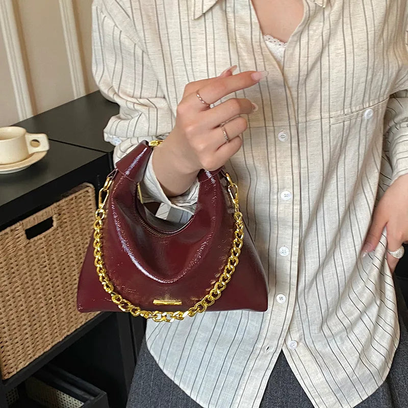 Soft handbag with gold tone chain – Burgundy bag held at the side | BTendance