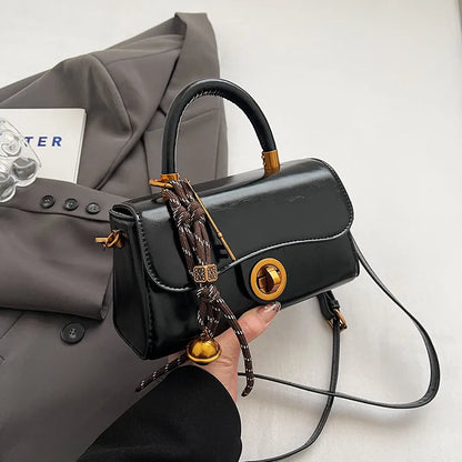 Structured top-handle flap handbag with round gold-tone clasp — black with scarf accent held in one hand | BTendance