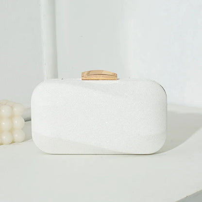 Rounded rectangular evening clutch with metal clasp — white front view on table | BTendance