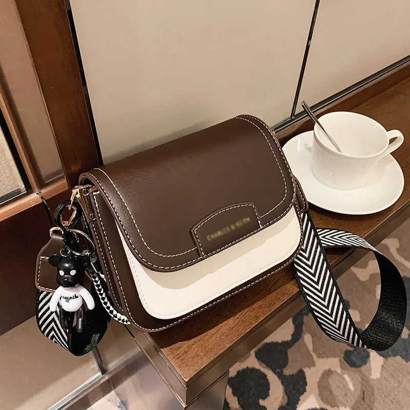 Colour block crossbody bag with patterned strap – Brown and cream bag with chevron strap on a table | BTendance
