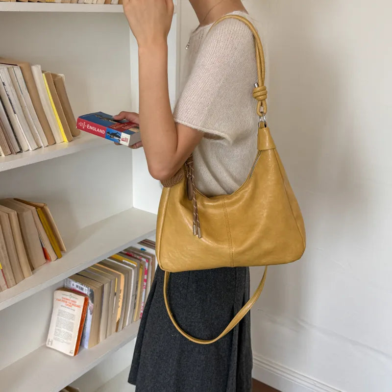 Slouchy shoulder bag with knotted strap and hanging charm — yellow worn on shoulder | BTendance