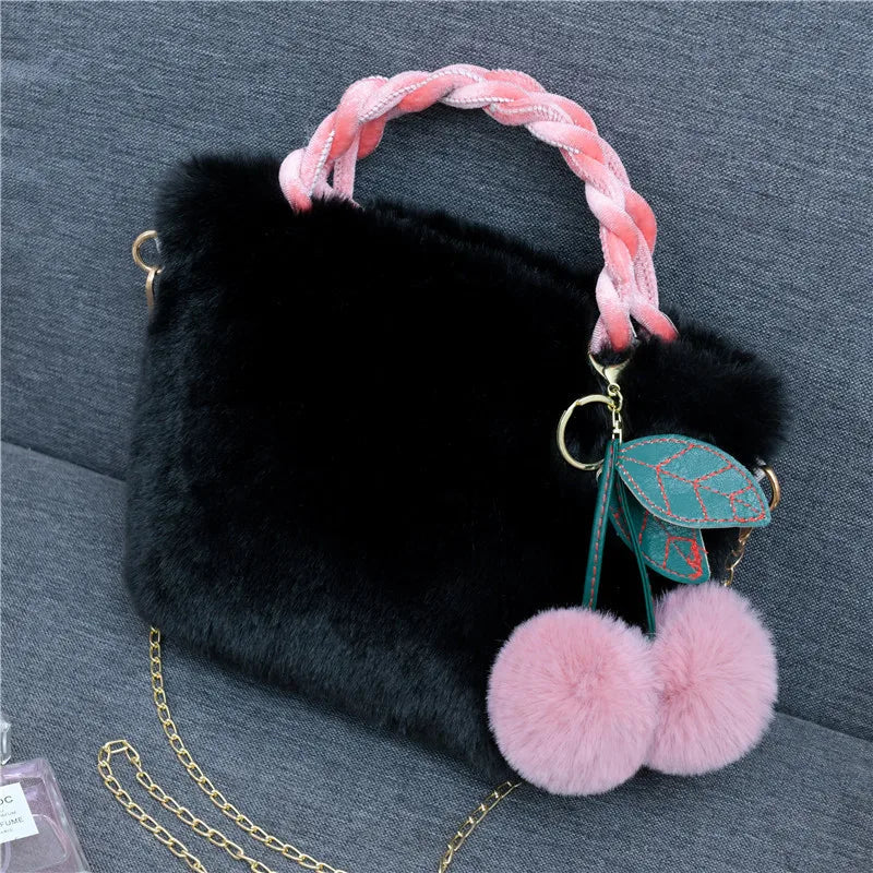 Plush handbag with twisted pink handles and pom-pom cherry charm — black on grey chair | BTendance