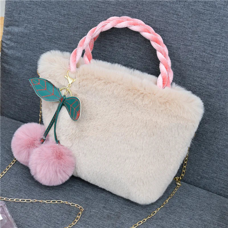Plush handbag with twisted pink handles and pom-pom cherry charm — cream on grey chair | BTendance