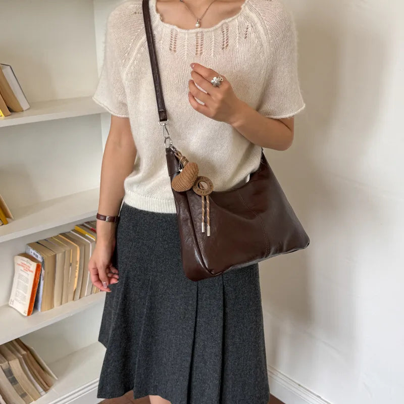 Slouchy shoulder bag with knotted strap and hanging charm — dark brown worn crossbody | BTendance