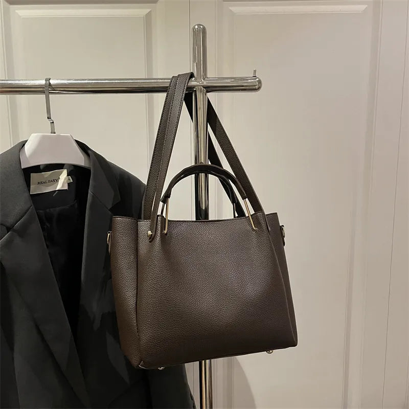 Textured bucket handbag with contrasting dark handles — dark brown hanging on clothing rack | BTendance