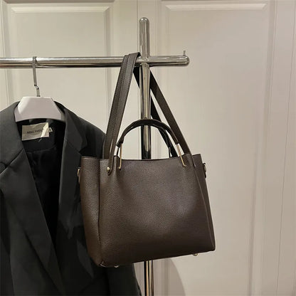 Textured bucket handbag with contrasting dark handles — dark brown hanging on clothing rack | BTendance