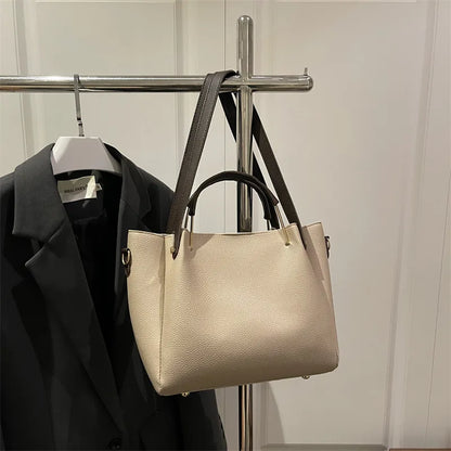 Textured bucket handbag with contrasting dark handles — beige hanging on clothing rack | BTendance