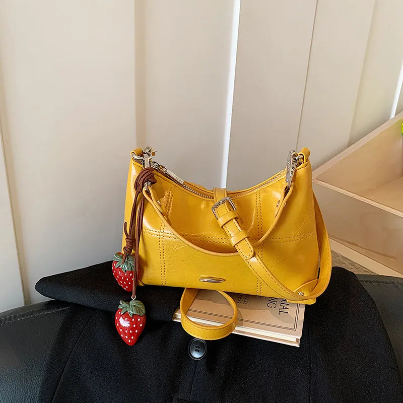 Glossy shoulder bag with strawberry charm – Yellow bag displayed on a table | BTendance