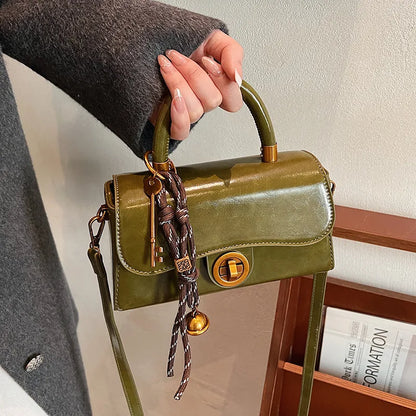 Structured top-handle flap handbag with round gold-tone clasp — green held by handle with scarf accent | BTendance