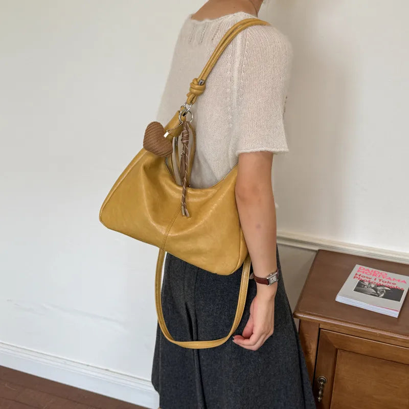 Slouchy shoulder bag with knotted strap and hanging charm — yellow worn on shoulder | BTendance