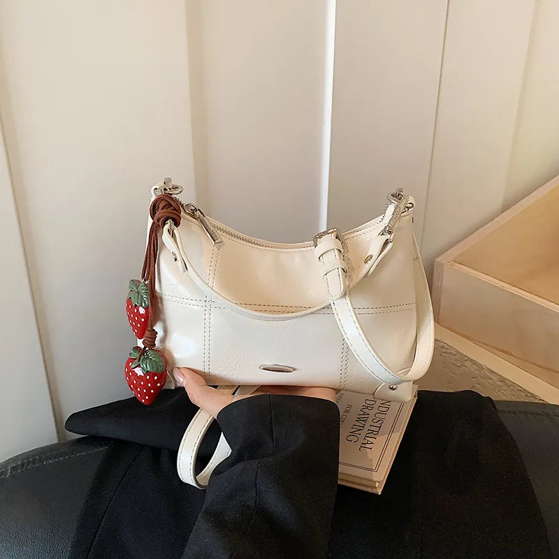 Glossy shoulder bag with strawberry charm – White bag, front view in hand | BTendance