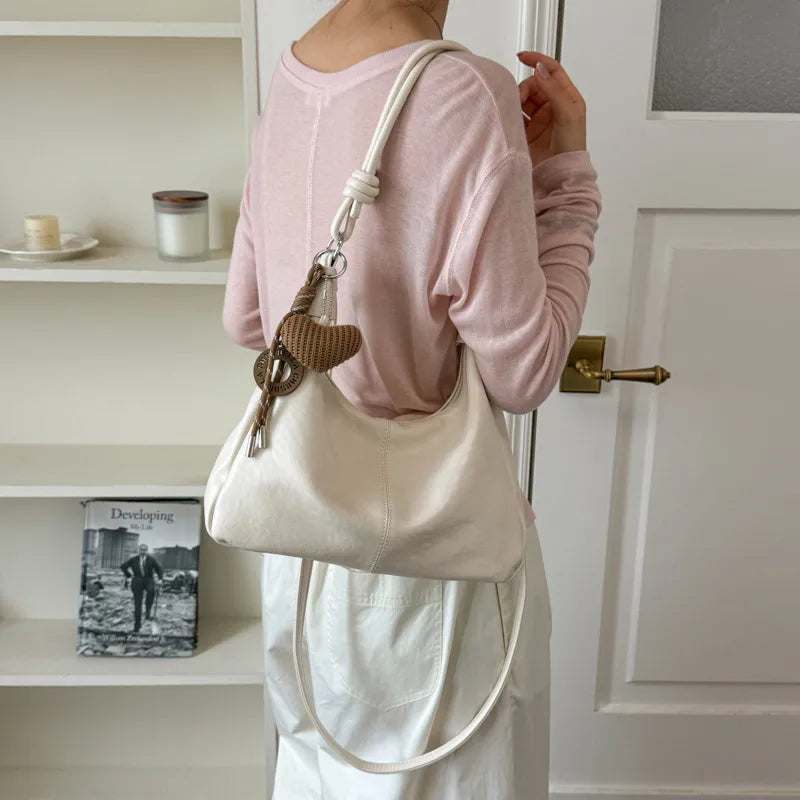 Slouchy shoulder bag with knotted strap and hanging charm — white worn on shoulder | BTendance