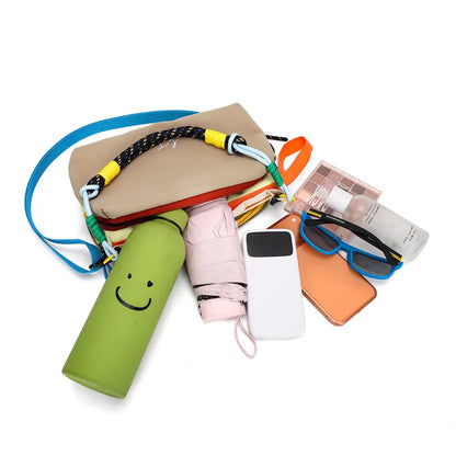 Color-block crossbody bag with rope handle — open bag with personal items arranged beside it | BTendance