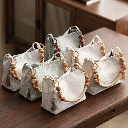 Floral shoulder bag with beaded handle – Assorted pale colours arranged on a table | BTendance
