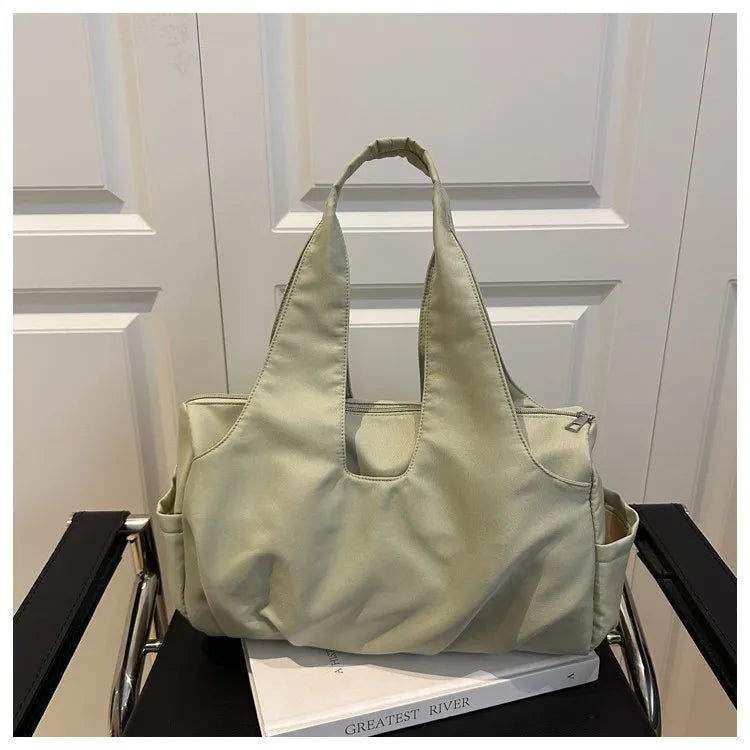 Soft shoulder tote with wide handles and side pockets — sage green on chair | BTendance