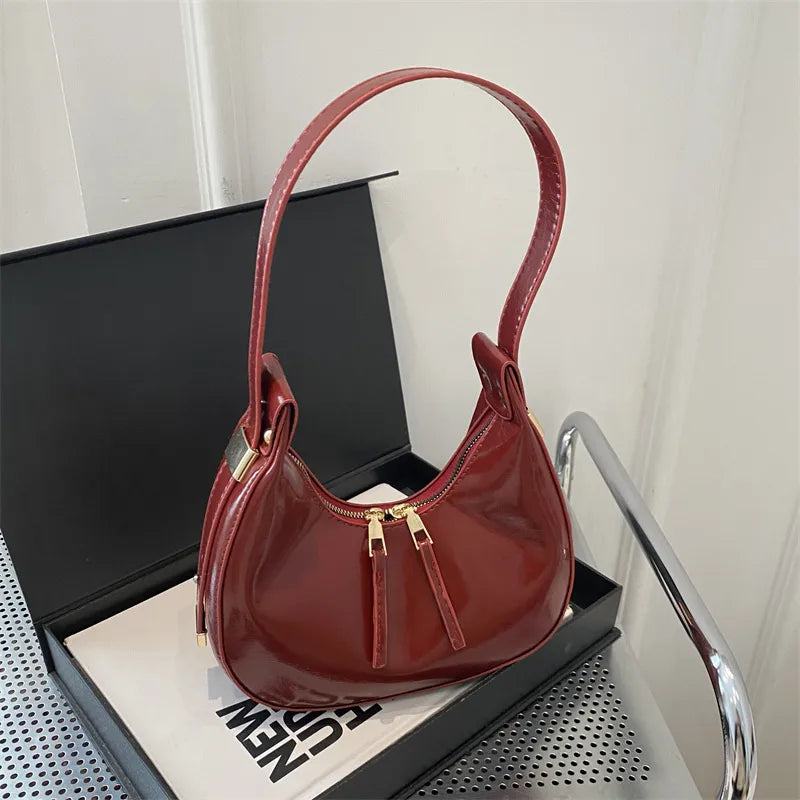 Curved zip shoulder bag – Burgundy bag displayed on a table | BTendance