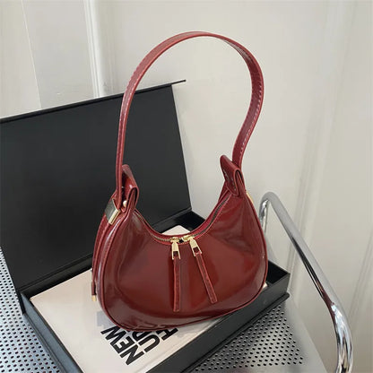 Curved zip shoulder bag – Burgundy bag displayed on a table | BTendance