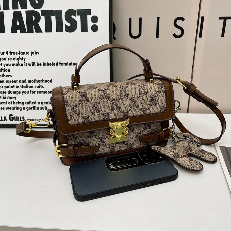 Bear pattern top handle bag with charm – Brown bag displayed beside a phone | BTendance