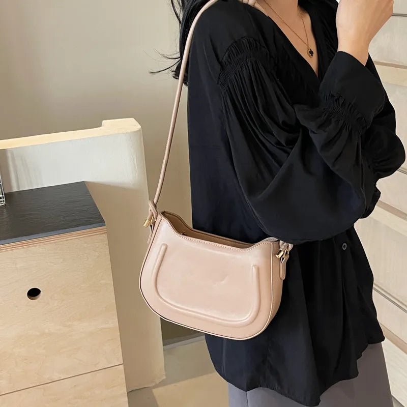 Curved shoulder bag with outlined front panel and knotted strap — cream worn on shoulder | BTendance
