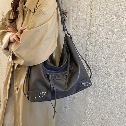 Slouchy shoulder bag with front zip and buckle details — grey worn over beige coat | BTendance