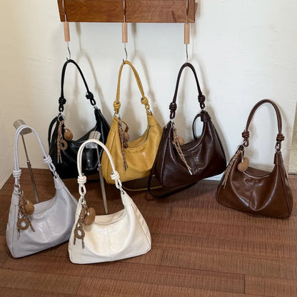 Slouchy shoulder bag with knotted strap and hanging charm — six colors grouped on display | BTendance