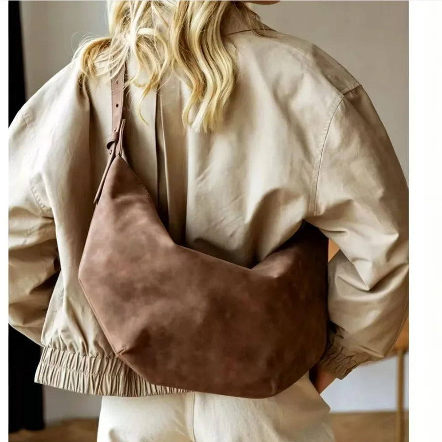 Crescent-shaped shoulder bag with adjustable strap — brown worn with beige jacket | BTendance