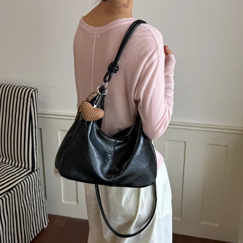 Slouchy shoulder bag with knotted strap and hanging charm — black worn on shoulder | BTendance