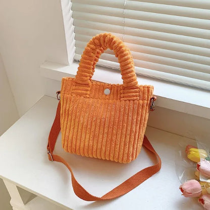 Ribbed plush handbag with rounded handles and long strap — orange near window | BTendance