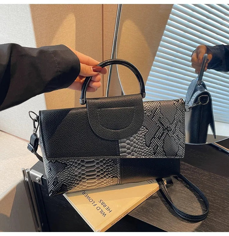 Structured handbag with contrasting reptile-texture panels — black and grey held by handle | BTendance