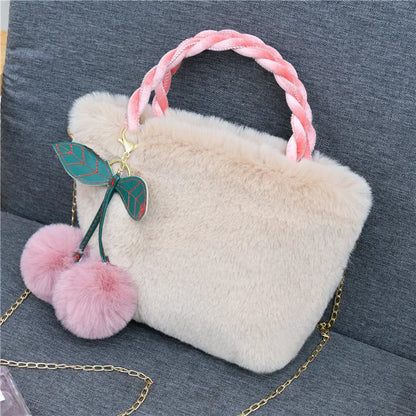 Plush handbag with twisted pink handles and pom-pom cherry charm — cream on grey chair | BTendance
